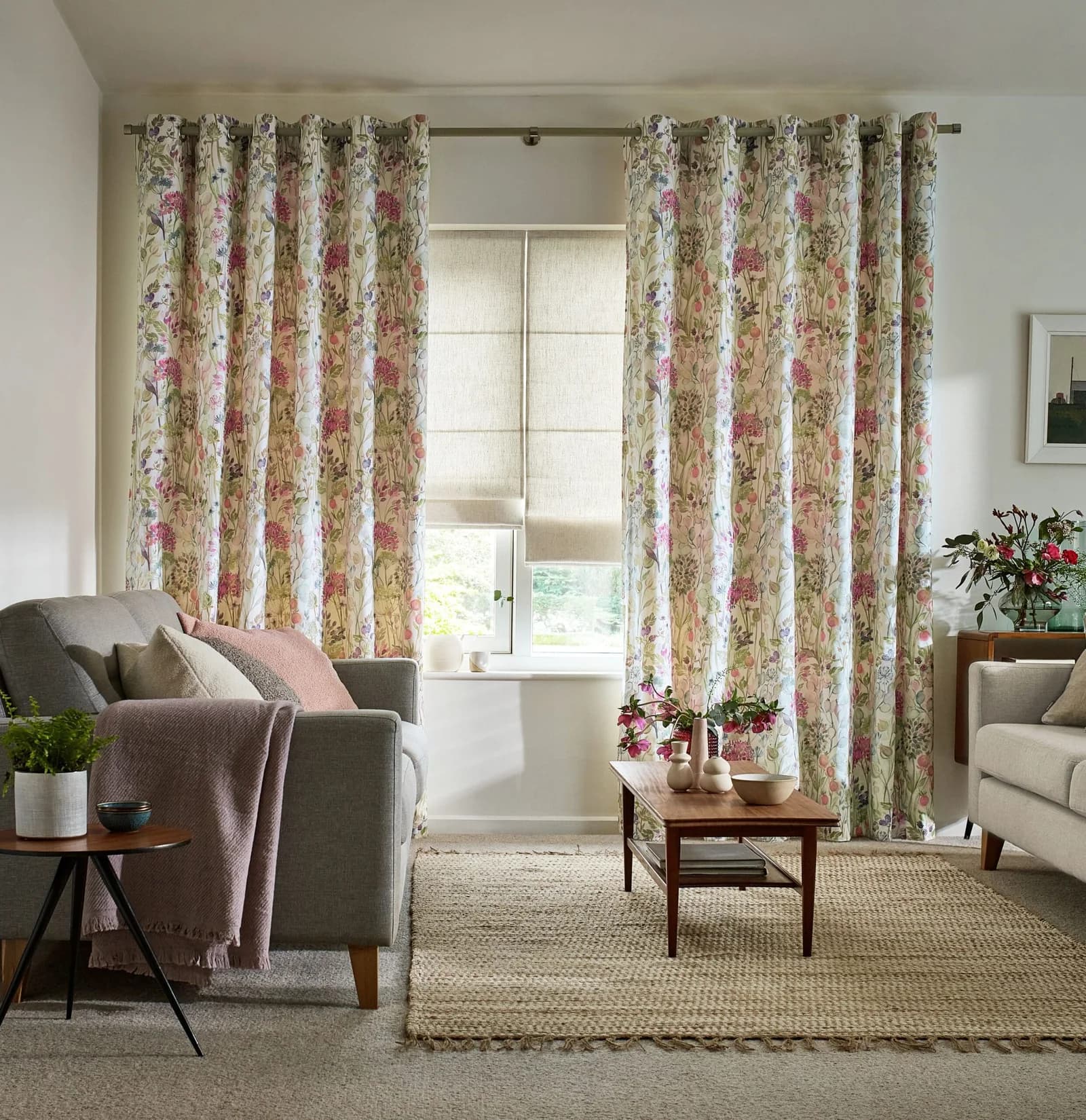 Floral eyelet curtains hung from a pole, rings visible along the heading