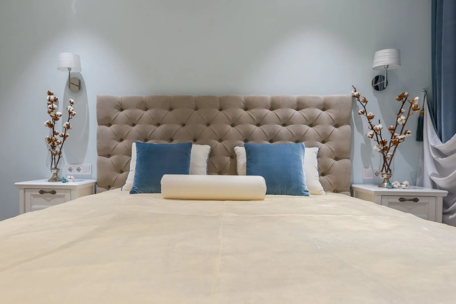 Pillows on a made bed beside a flowered nightstand